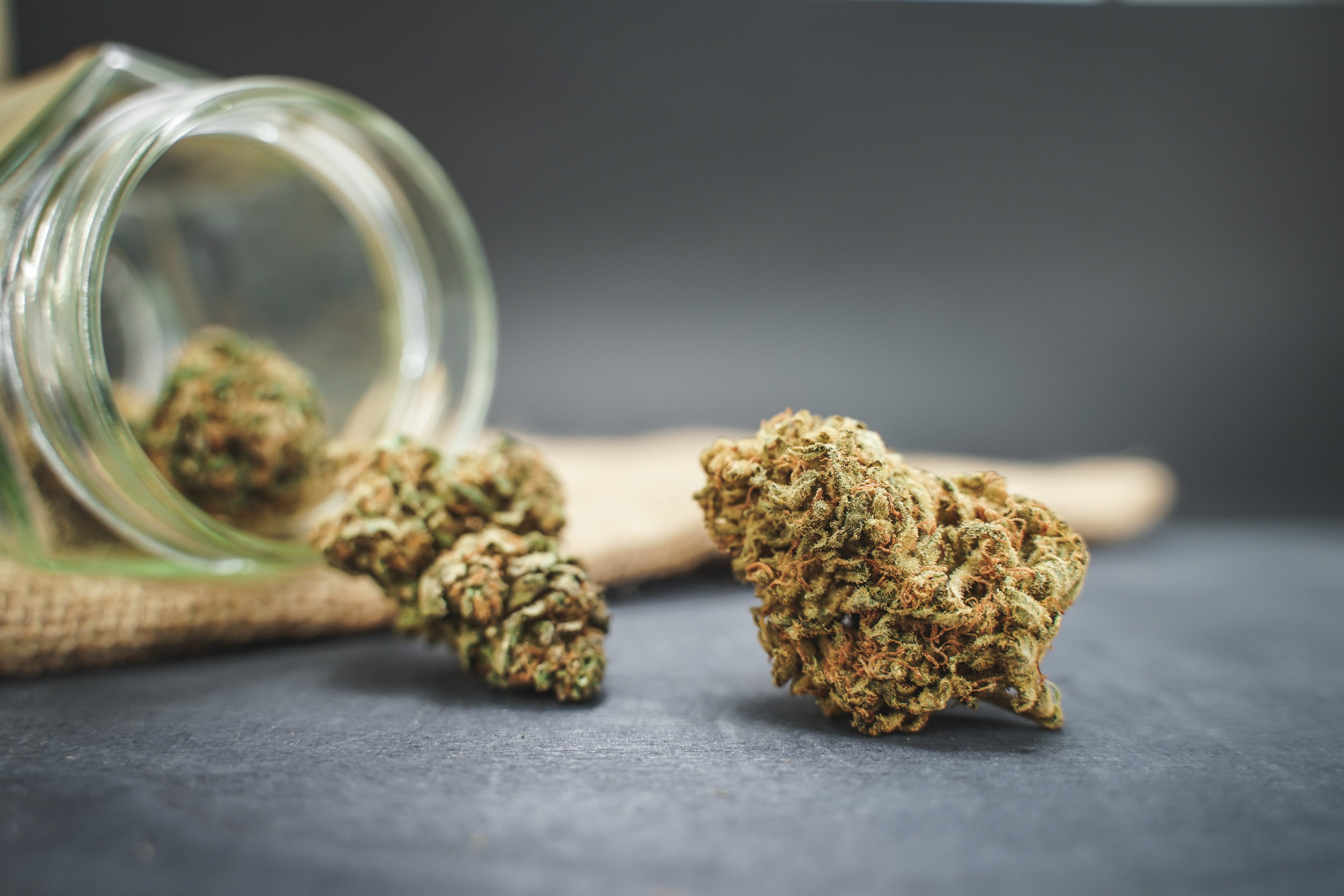Getrocknete CBD Blüten neben einem geöffneten Glas
