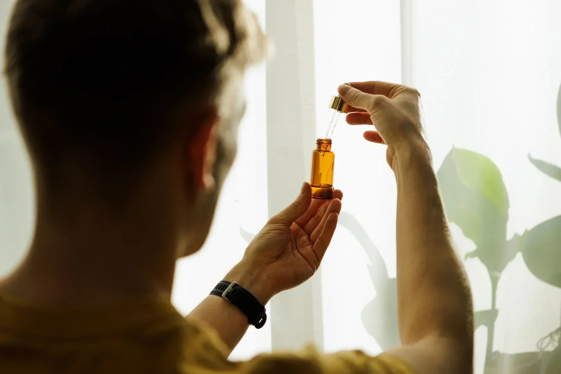 Person prüft CBD Öl in einer Pipettenflasche am Fenster