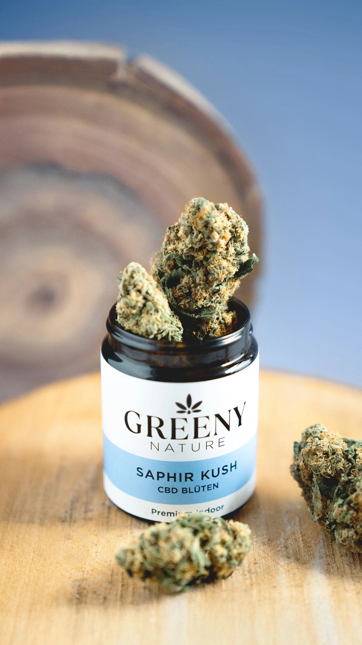 GreenyNature Saphir Kush Candy Kush CBD Blüten im geöffneten Glastiegel neben weiteren Blüten
